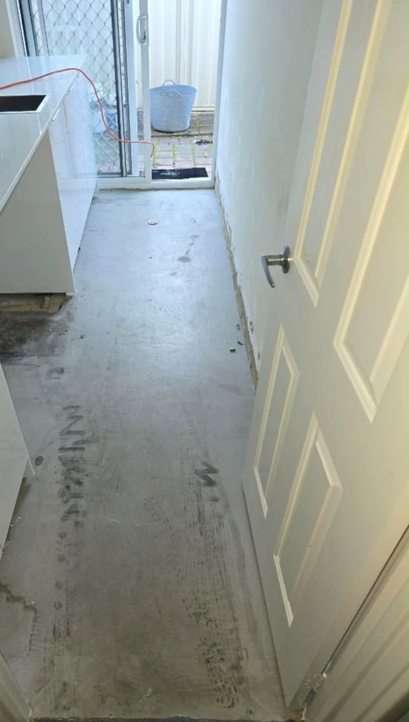 Stripped laundry with bare concrete floor before renovation by Luxe Flow Plumbing